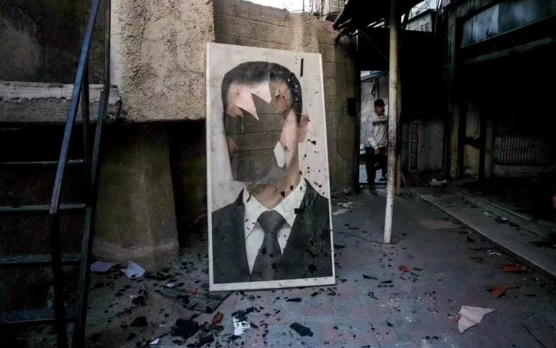 Síria: retrato rasgado do presidente sírio deposto Bashar al-Assad em uma instalação de segurança governamental saqueada, em Damasco, em 8 de dezembro de 2024.